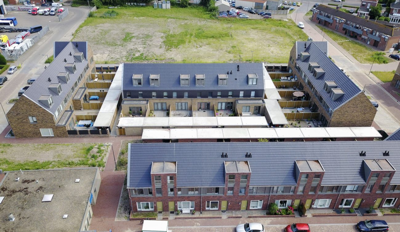 Vogelvlucht De Driesprong Breda: binnenhof met daktuinen, galerijen, rijwoningen en carports. bomen.