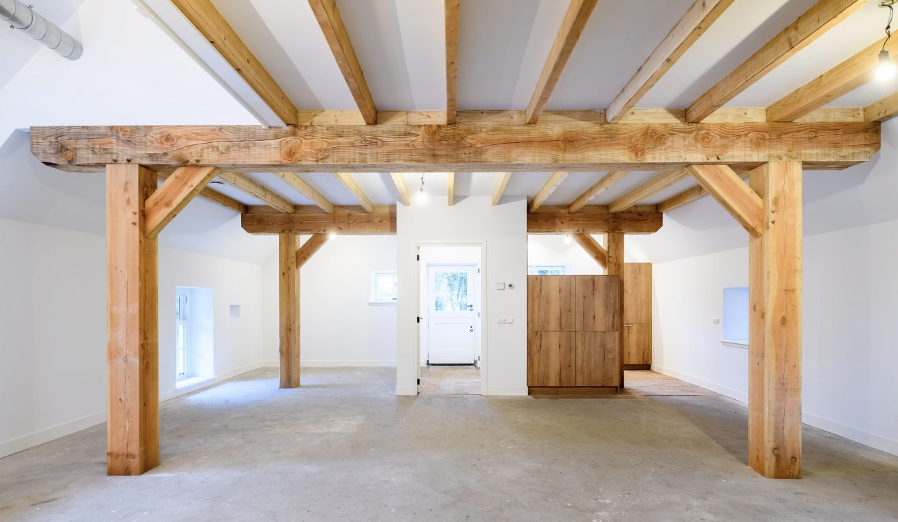 Interieur woonboerderij Naardermeer: open ruimte met eiken gebinten, zichtbare balklaag en wit stuc