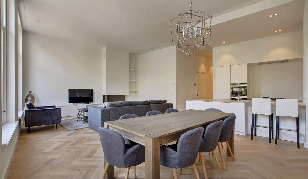 Woonruimte Oudezijds Voorburgwal: eethoek voor acht, lounge met tv en minimalistische kastenwand