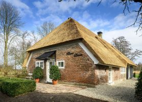 Gerestaureerde woonboerderij Naardermeer: baksteen, wit houtwerk, rieten dak en groene erfhaag
