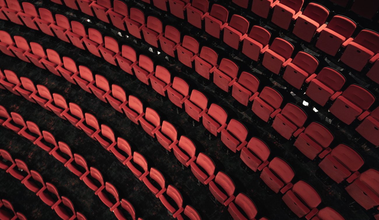 Close-up van gebogen rijen rode theaterstoelen, van bovenaf gezien.