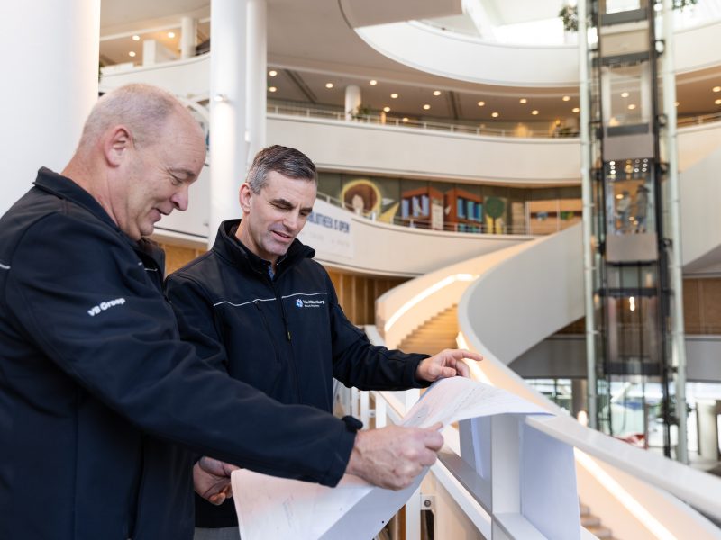 Technici bekijken bouwtekeningen in een modern atrium.