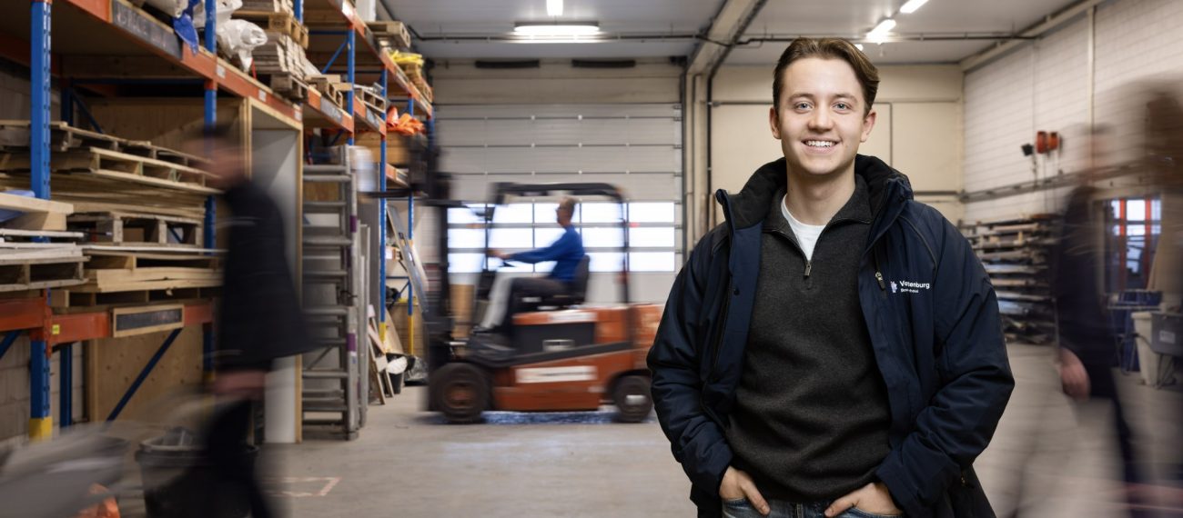Een medewerker poseert waarbij op de achtergrond veel beweging in een werkplaats is