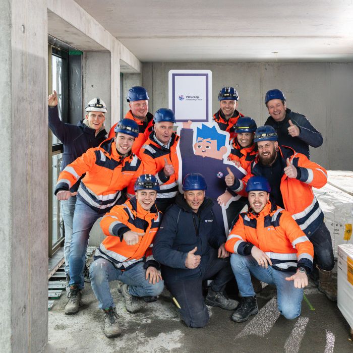 Een enthousiaste groep collega's poseert met mascotte Bobby in het midden