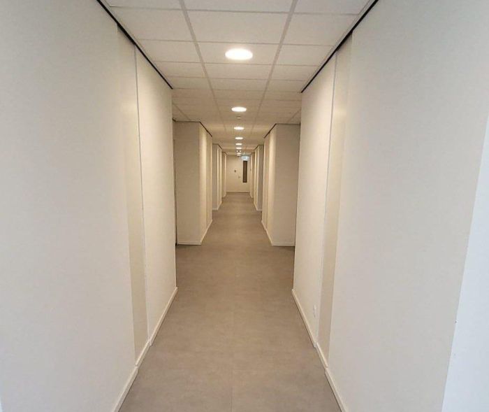 Transformatie voormalig hotel Born – lange, lichte gang met repetitieve nissen, deuren en plafondspots