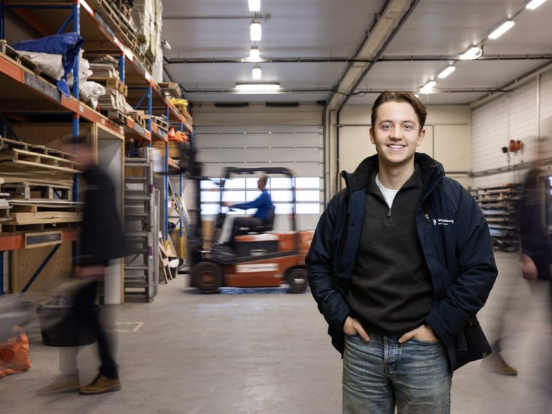 Een medewerker poseert waarbij op de achtergrond veel beweging in een werkplaats is