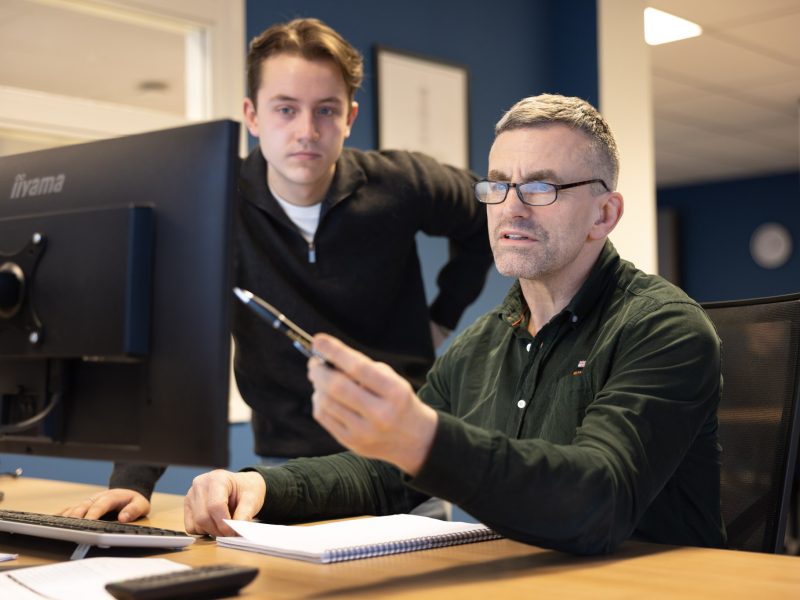 Twee collega's overleggen, waarbij een persoon naar een beeldscherm wijst