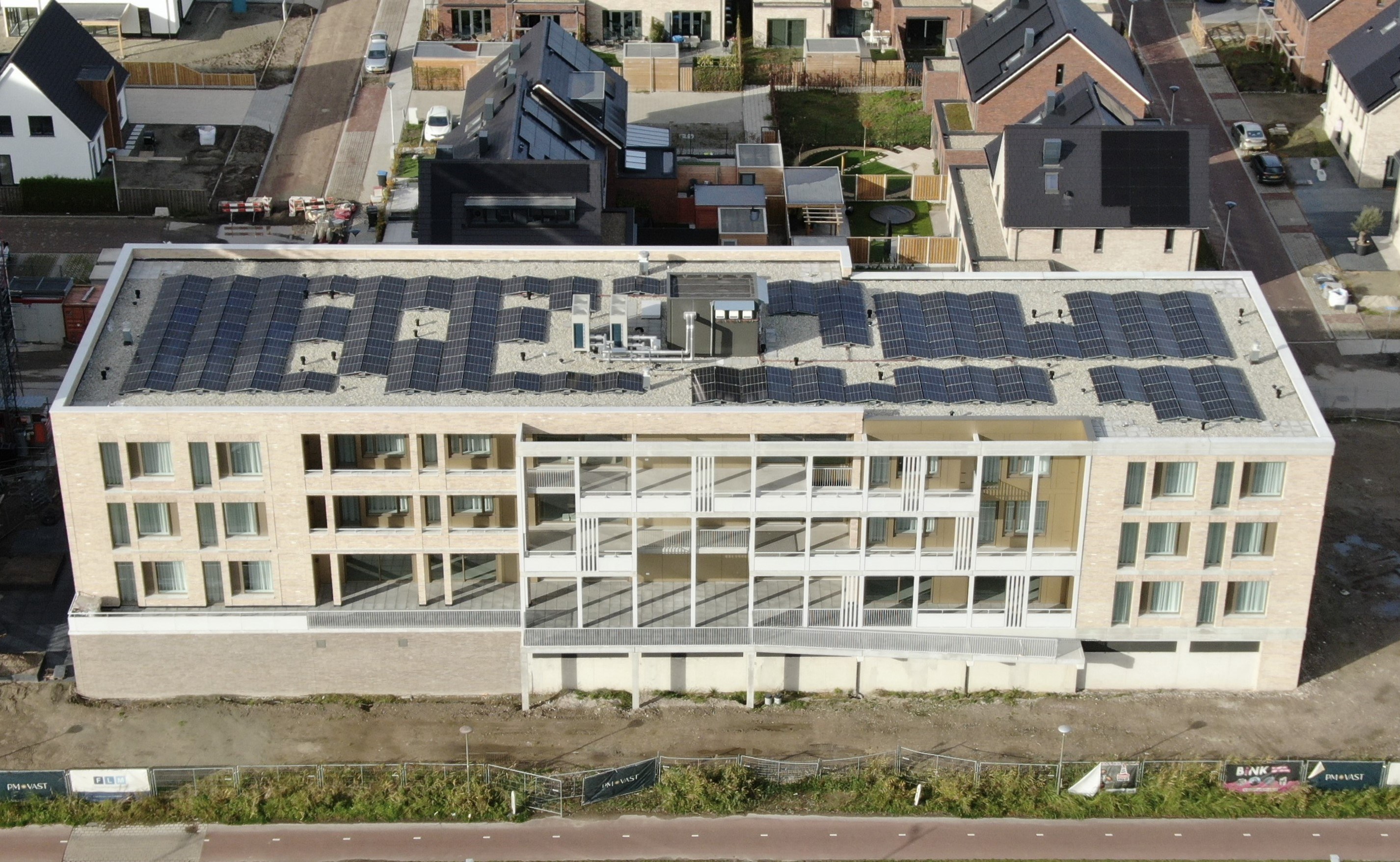 De Baron Bergen op Zoom: gevel met witte kaders, balkons en galerijen; zonnepanelen dak, bouwterrein