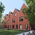 Impressie Stadsgeluk Utrecht – moderne grachtenwoningen met variërende baksteen- en witte gevels, grote ramen en zadeldaken aan de kade, met passerende sloep.