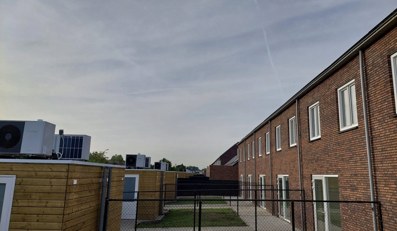 Nieuwbouw Bredeweg Roermond – achtergevels rijwoningen met witte kozijnen, tuinen met gaashek en houten bergingen met buitenunits