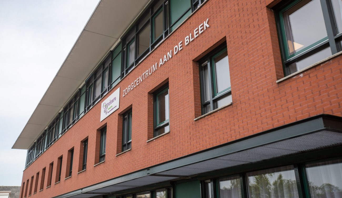 Zorgcentrum Aan de Bleek Schinveld: gerenoveerde baksteengevel met groene kozijnen en luifel