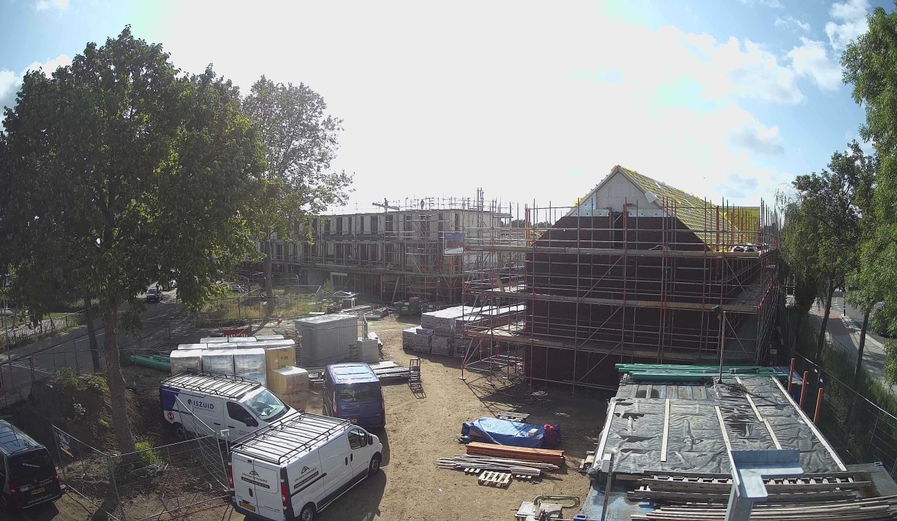 Nieuwbouw Emmalaan Roermond – bouwplaats met rijwoningen in steigers, dakisolatie in aanbouw en busjes/materialen op het terrein
