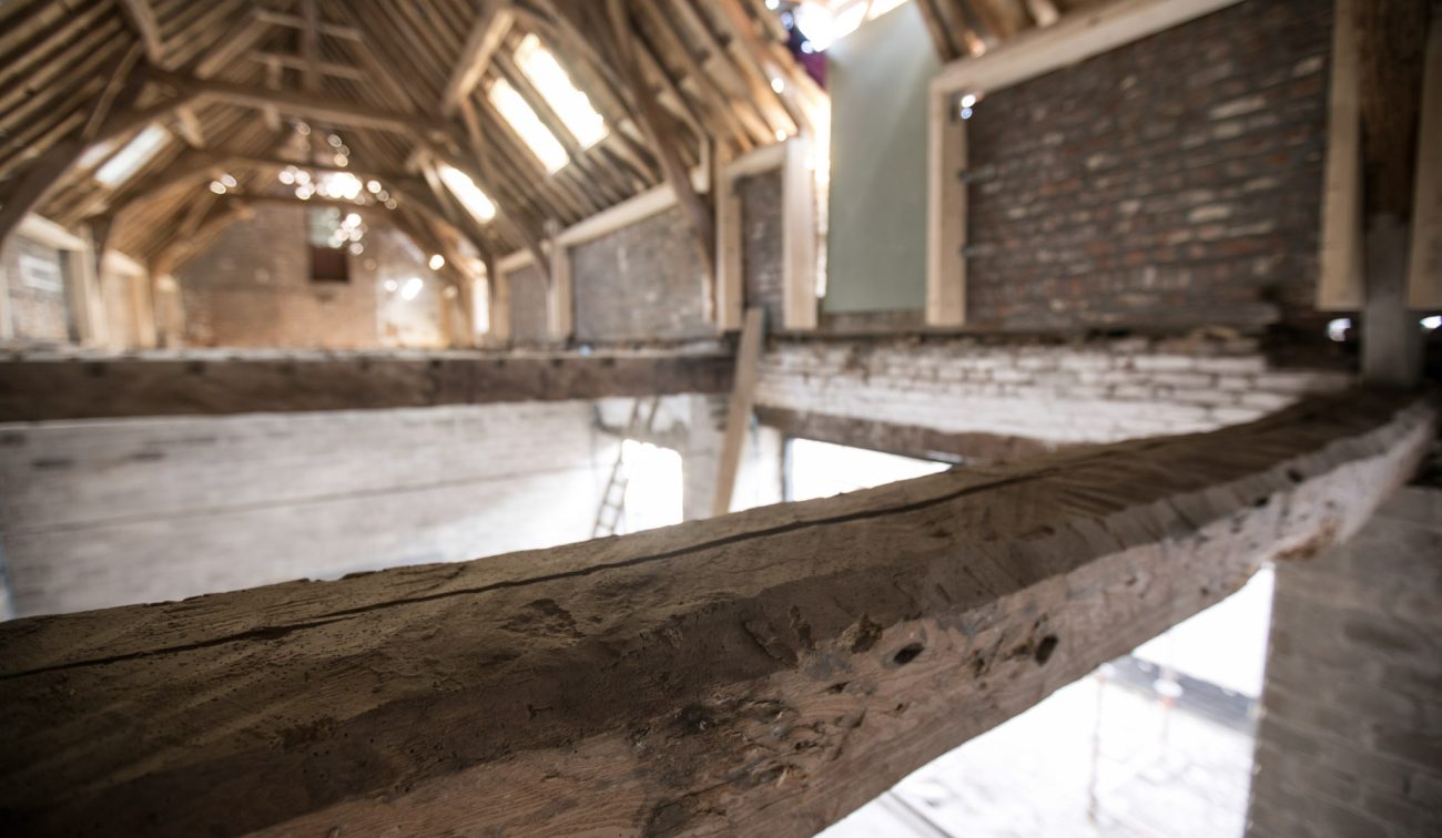 Detail robuuste eiken balk in open kapconstructie tijdens restauratie — Herbestemming hoeve tot appartementen Maastricht