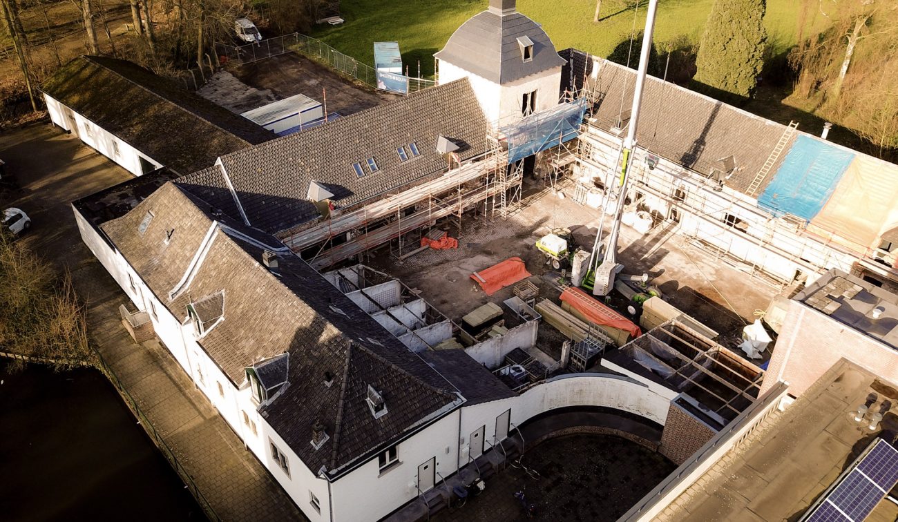 Luchtfoto U-vormige monumentale hoeve met steigers en bouwkraan rond open binnenhof — Herbestemming hoeve tot appartementen Maastricht