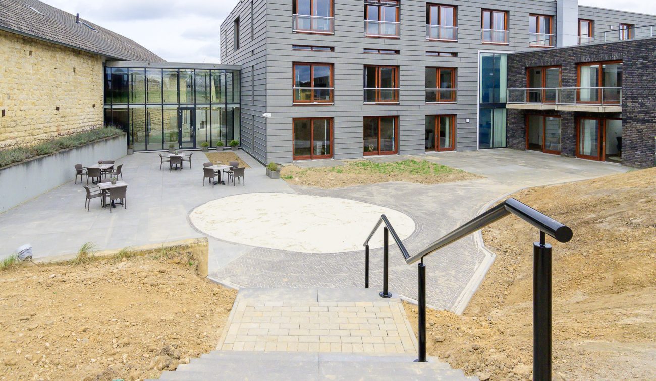 Binnenhof Hoeve Overhuizen met terraszitjes, trappartij en moderne glazen verbinding.
