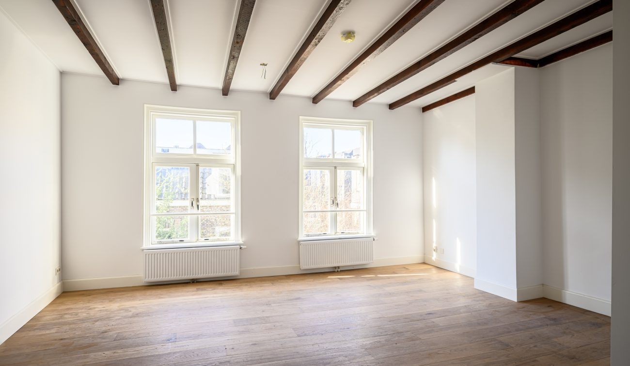 Transformatie Lijnmarkt & Visschersplein Utrecht – lichte kamer met twee hoge ramen, zicht op stadstuin, houten vloer.