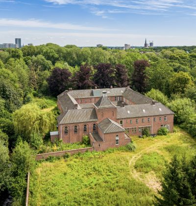 Landgoed met bakstenen gebouw midden in bosrijk landschap vanuit vogelperspectief