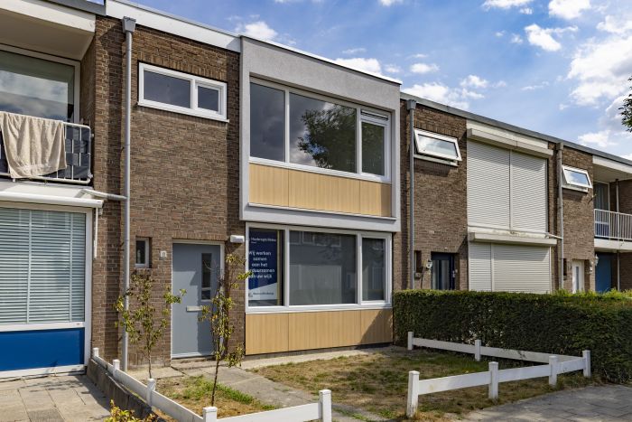 Groot onderhoud Staatsliedenbuurt Tilburg – rijwoning met vernieuwde voorgevel, isolerende gevelpanelen in houtlook en wit kader, nieuwe kozijnen en groot raam, tussen bestaande woningen.