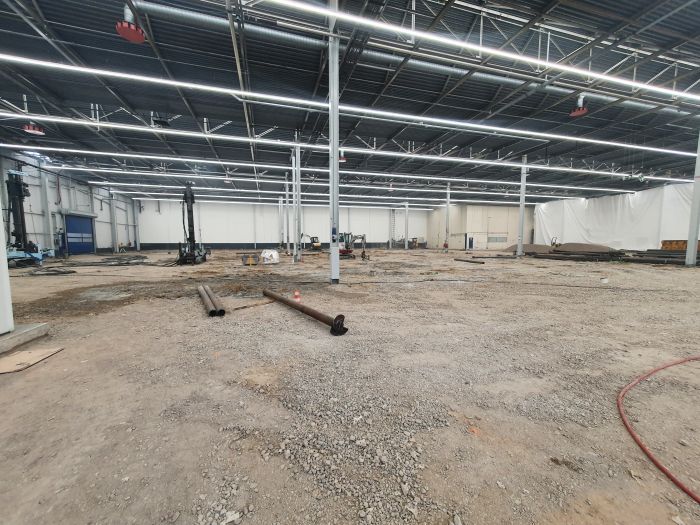 Renovatie van de betonvloer in hal A50 bij DAF Eindhoven, met opengebroken vloer, bouwmaterieel en voorbereidende werkzaamheden in de fabriekshal.