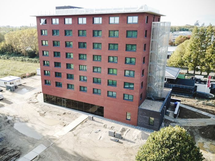 Nieuwbouw Bastion Hotel Geleen – luchtfoto van rood bakstenen hotel met glazen trappenhuis en glazen plint, terrein in afbouwfase