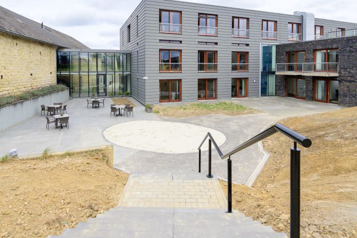Binnenhof Hoeve Overhuizen met terraszitjes, trappartij en moderne glazen verbinding.