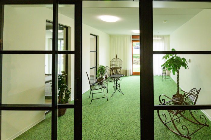 Serre-achtige zitruimte in Hoeve Overhuizen met groen tapijt en smeedijzeren meubels